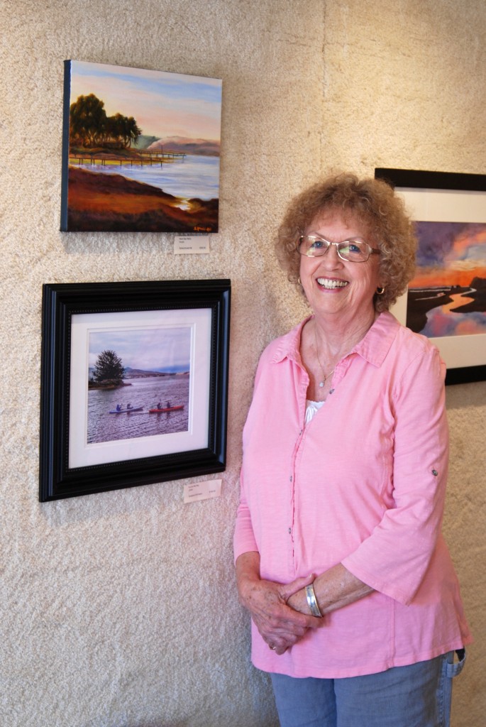 Sylvia Arnold-Hill poses with her acrylic painting of the back bay (top left on wall)