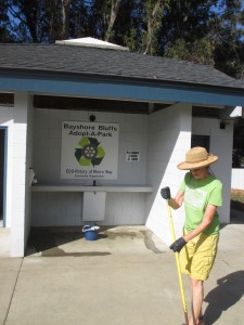 Charlotte sweeps the sidewalk near the Eco Rotary Club’s Adopt-A-Park sign.