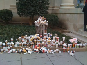 Coffee cups overflow this trashcan.