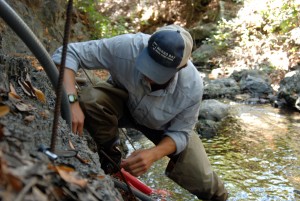 Shane utilizes the stream bank to anchor the end of the pressure transducer.