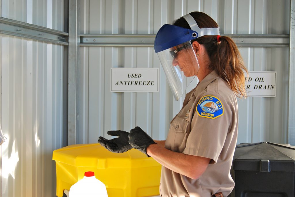 Becka Kelly, Harbor Department Supervisor, dons protective gear before pouring some oil into the drum to be recycled.