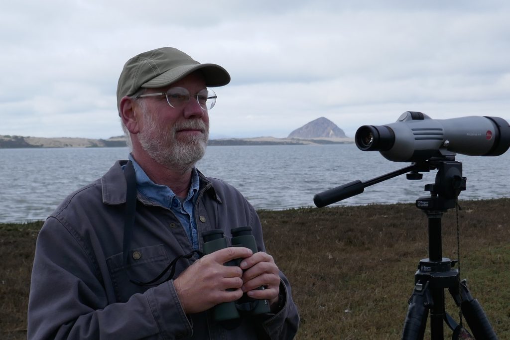 John Roser stands near the Morro Bay estuary, scope and binoculars at the ready. 