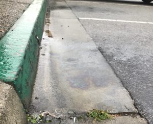 Rain washes oil from a parking lot in Morro Bay down the gutter and into a storm drain.