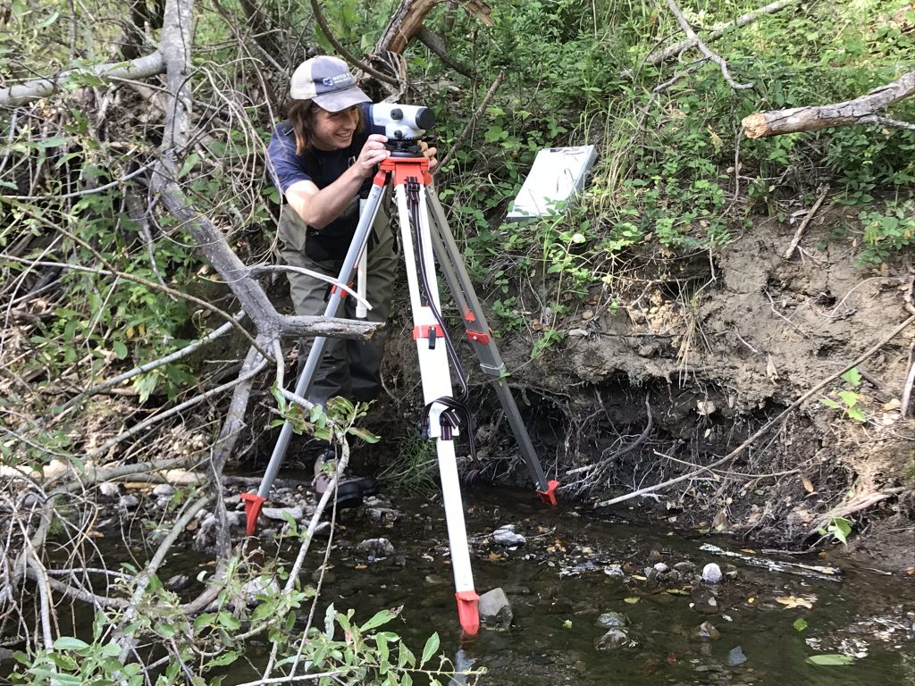 Tyler, Field Technician, surveys stream height. 