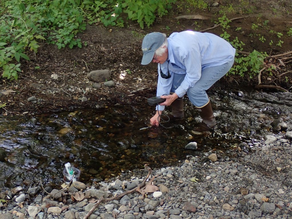 Shows a volunteer conducting water quality monitoring