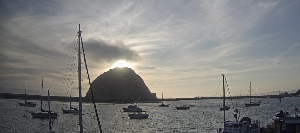 Morro Rock and clouds illuminated from behind.