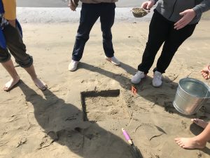 Here, Morro Bay High School students show off their precisely excavated quadrat, or monitoring area, as they sift sand samples for microplastic materials.