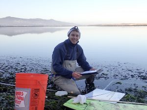 Bret Fickes, Monitoring Projects Manager, Morro Bay National Estuary Program kneels in an eelgrass bed while monitoring its health.